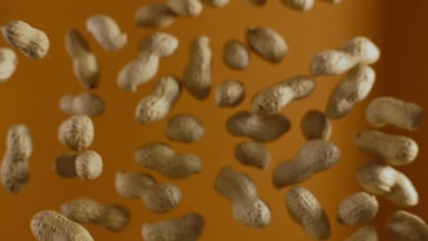 Amendoins caindo em câmera lenta sobre o fundo laranja — Vídeo de Stock