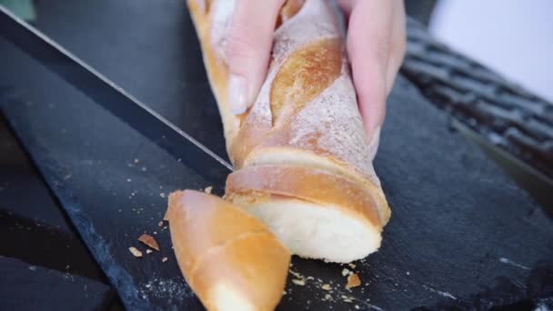 Θηλυκό κόβει το ζεστό φρέσκο ψωμί στην κουζίνα — Αρχείο Βίντεο
