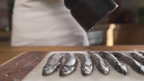 끓는 기름에 튀기기 위하여 생선에 후추를 친다 — 비디오