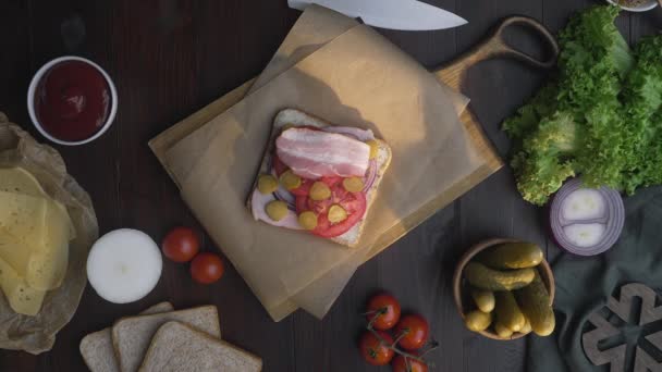 Плоский шар виготовлення бутерброду з нарізаним солоним беконом та овочами на дерев'яній дошці — стокове відео