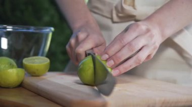Ev hanımı tahtadaki keskin bıçakla limonu ikiye böler.