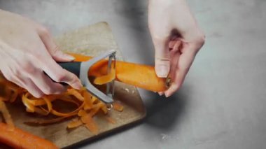 Ev hanımı sebze salatası için havuç soyar.