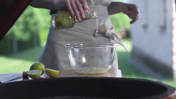 Hemmafru häller ut olivolja till skålen nära öppen eld — Stockvideo