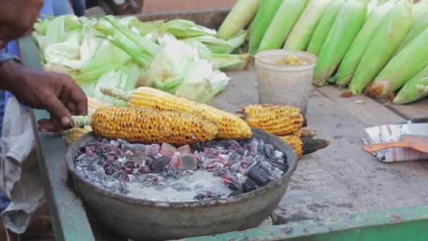 Man friet maïs op levende kolen buiten — Stockvideo