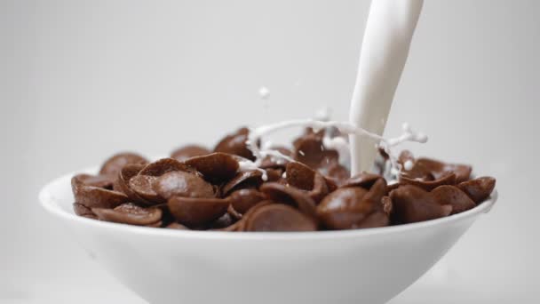 Süt, çikolatalı mısır gevreğiyle yavaş çekimde kaseye dökülür. — Stok video