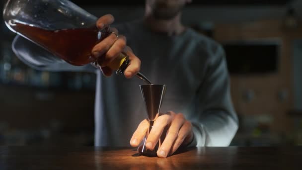 Barman nalewa whisky do jiggera, a następnie do szklanki z lodem — Wideo stockowe