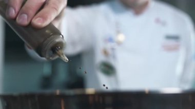 Şef yavaş çekimde yemek pişirmeye zeytin yağı ekliyor.