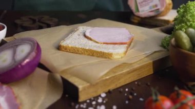 Şef fast food sandviçine füme jambon ekliyor.