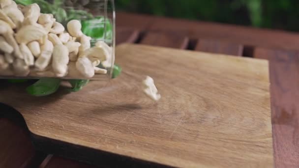 Орехи кешью падают на деревянную доску — стоковое видео