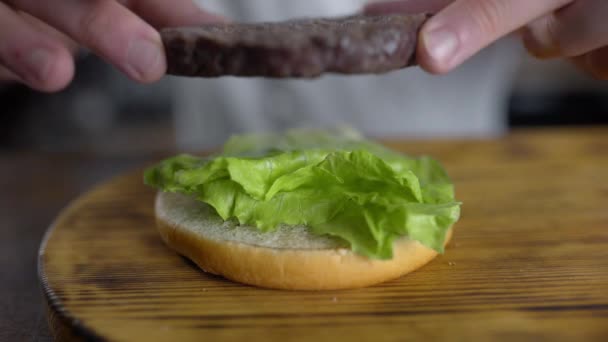 Şef hamburger pişirir ve taze yeşil salata yapraklarına pirzola koyar. — Stok video