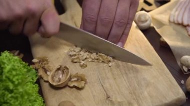 Şef tahta tahtada ceviz keser, salata pişirir.
