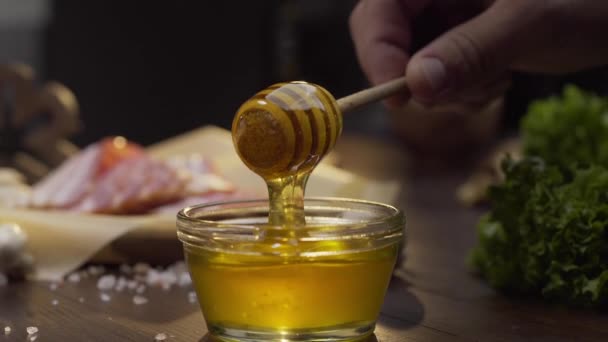 Szef kuchni zanurza drewniany miód kij do szklanej miski — Wideo stockowe