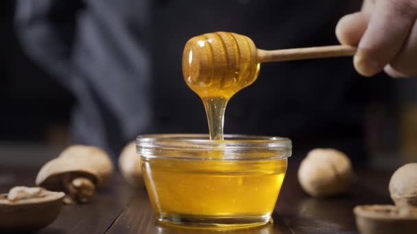 Trempettes chef bâton de miel en bois dans le bol en verre Séquence Vidéo Libre De Droits