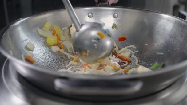 Шеф-повар жарит овощи с лапшой и рыбу в горячем воке в замедленной съемке — стоковое видео