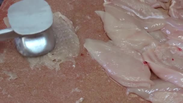 Шеф-повар делает отбивные из куриной грудки стальным кухонным молотком на деревянной доске — стоковое видео