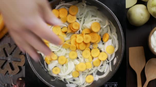 Koch gibt gehackte Karotte zur Zwiebel in die heiße Pfanne — Stockvideo