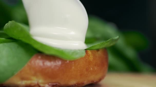 Chef ajoute de la sauce à la crème au hamburger avec des légumes et des petits pains verts — Video