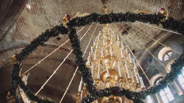 Lámpara de araña masiva con velas bajo la cúpula de la antigua iglesia — Vídeos de Stock