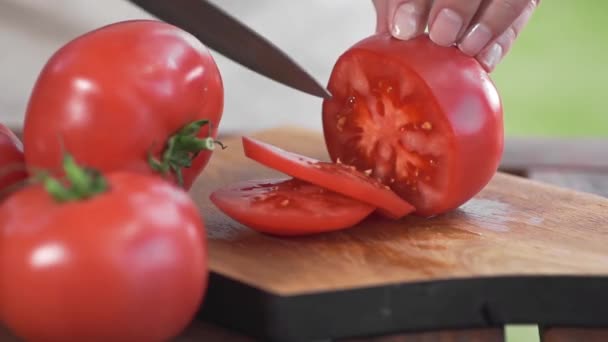 나무 도마 위에 날카로운 칼로 얇게 썬 토마토를 요리한다 — 비디오