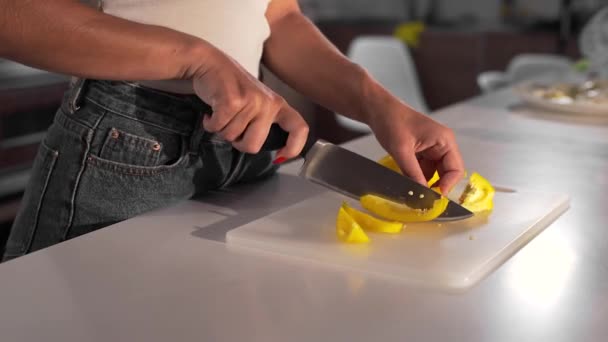 Kobieta tnie żółty pieprz ostrym nożem na desce — Wideo stockowe
