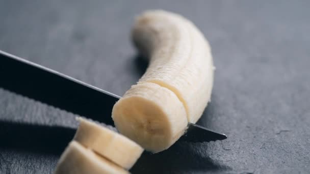 Mulher corta banana em uma tábua — Vídeo de Stock