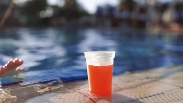 Жінка плаває до краю басейну приймає свіжі сокові напої — стокове відео