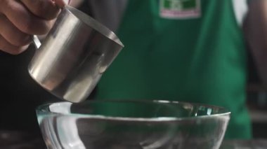 Aşçı, hamur işi pişirmek için cam kase malzemelerine krema ekler.