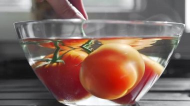 Aşçı domatesleri sıcak suyla dolu cam bir kasede kurutur.