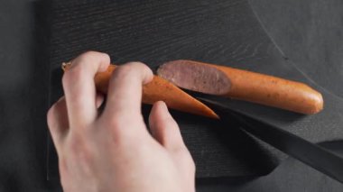 Aşçı ahşap tahtada keskin bıçakla sosis keser.