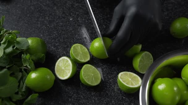 Le cuisinier coupe les citrons verts mûrs par un gros couteau tranchant — Video