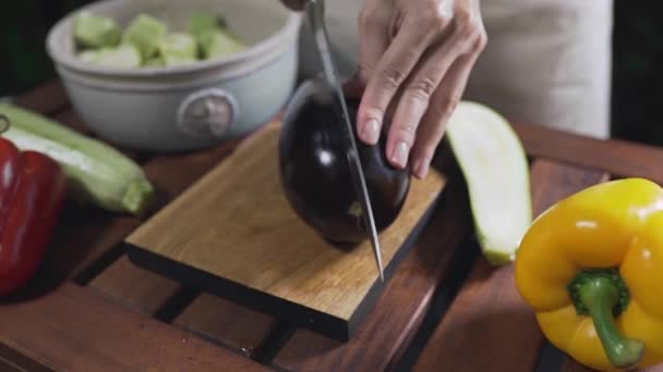 Der Koch schneidet die Auberginen auf das Holzbrett — Stockvideo