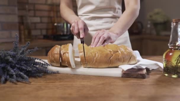 O cozinheiro corta pão branco na mesa da cozinha — Vídeo de Stock
