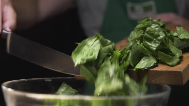 Der Koch gießt gehackten Spinat vom Schneidbrett in die Glasschüssel — Stockvideo