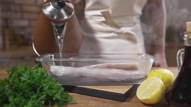 Der Koch gießt rohen Fisch mit kochendem Wasser — Stockvideo