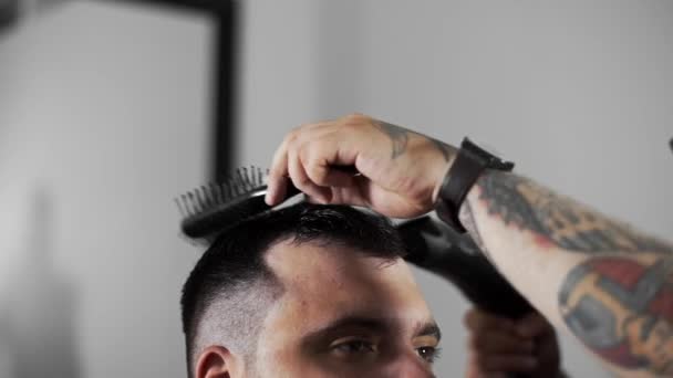 Barbeiro seca o cabelo e faz estilo de cabelo para o cliente na barbearia — Vídeo de Stock