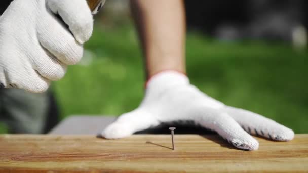 Homme en gants de travail marteaux l'ongle en plein air homme réparations meubles — Video