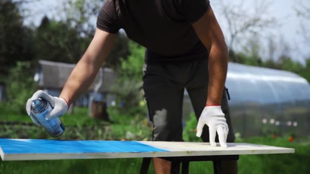 Mans main dans les pulvérisations de gants de travail peinture avec pulvérisation peut à la surface en bois — Video