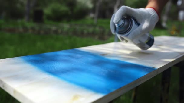 Mans main dans les pulvérisations de gants de travail peinture avec pulvérisation peut à la surface en bois — Video