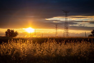 Yüksek voltajlı elektrik direkleriyle gün batımı manzarası