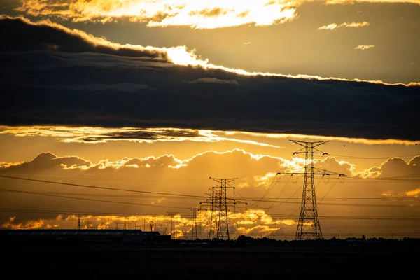 Yüksek voltajlı elektrik direkleriyle gün batımı manzarası