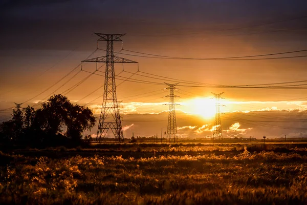 Yüksek voltajlı elektrik direkleriyle gün batımı manzarası