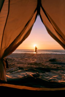 Turuncu ve gri çadırın kapısından yaz kampına bakıyorum..