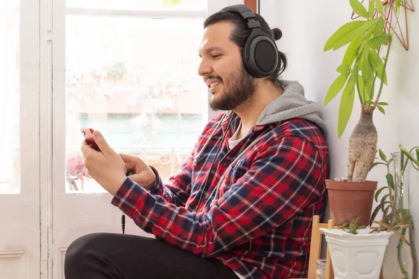 Genç adam kulaklıkla müzik dinliyor.