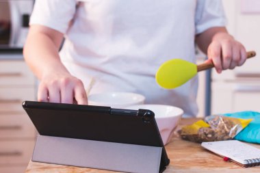 Yemek pişirirken tabletten yemek tarifi okuyan kişi