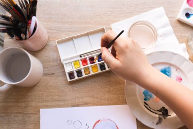 El, suluboya ile resim yapmak için fırça kullanır