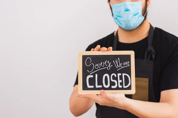 person with facial mask holds a sign saying 