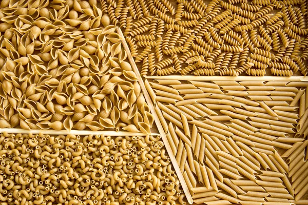 Assorted whole wheat pasta on wooden tray