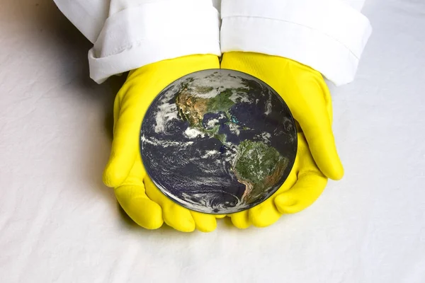 Planet earth in hands with yellow lab gloves