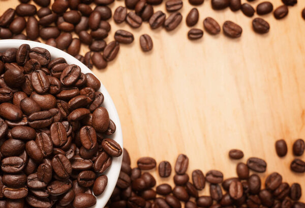 Close up shot of coffee beans on wooden vintage chopping board with copy space.