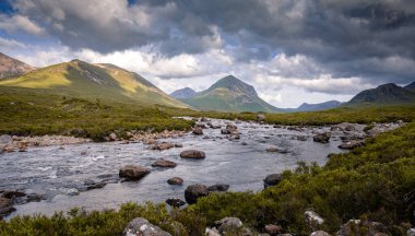 Sligachan nehri ön planda, Marsco zirvesine çıkıyor. Kızıl Tepeler 'de (Red Cuillin) İskoçya yazının kasvetli öğleden sonrası sahnesi. Yamaçlarda güzel ışık oyunları var Bulutlar ve alçak güneş sayesinde.